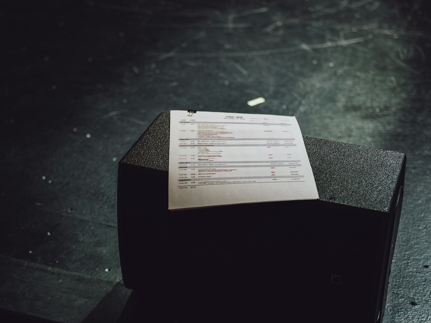 Horario de eventos impreso en papel sobre un altavoz en un escenario.